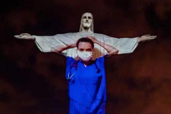 Christ the Redeemer lit up with images of frontline workers projected.