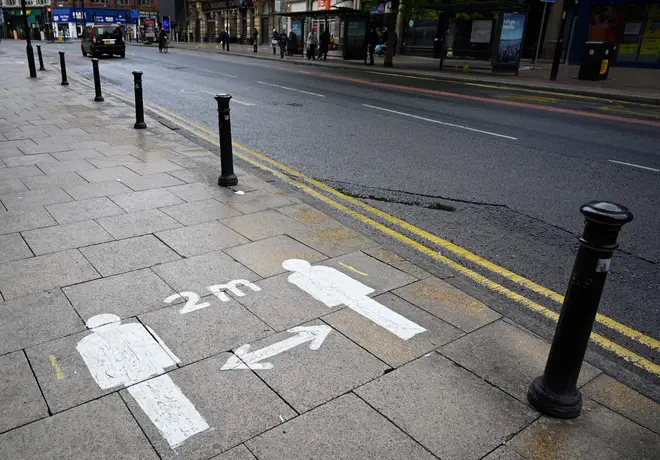 Markings on the pavement advises pedestrians to stay two meters (2M) apart