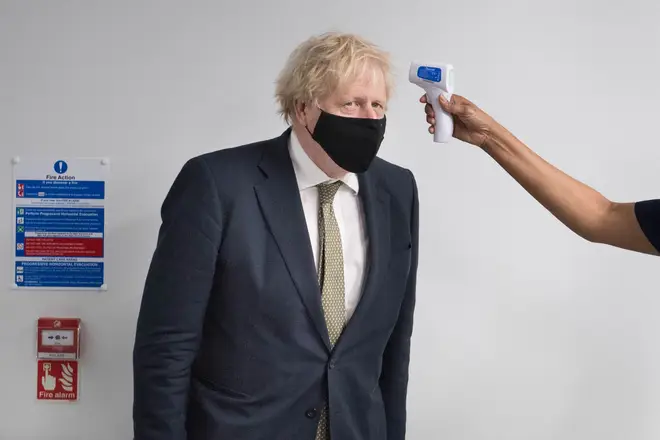 Prime Minister Boris Johnson has his temperature taken during a visit to view the vaccination programme at Chase Farm Hospital