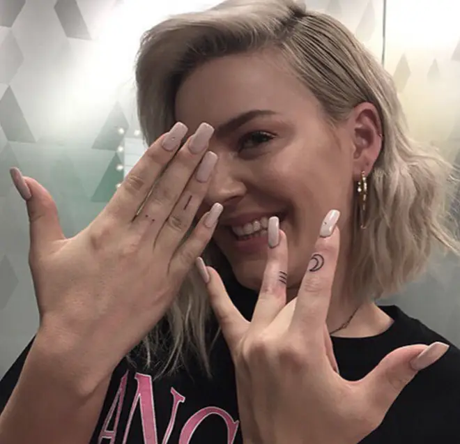 Anne-Marie has four different tatts on her fingers.