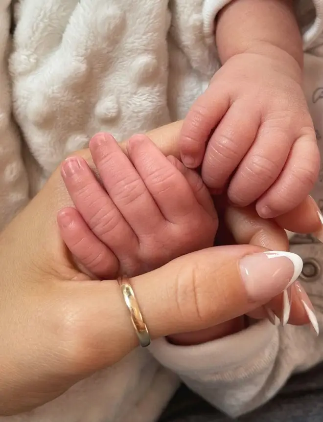 Jena Frumes holding her baby boy's hand