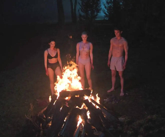 Betty, Archie and Veronica stood around a fire in their underwear, covered in blood, before they burnt Jughead's beanie.