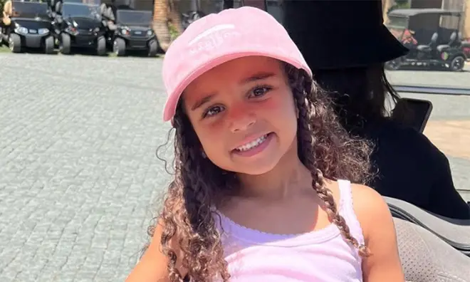 Dream Kardashian smiling on the back of a golf buggy wearing all pink
