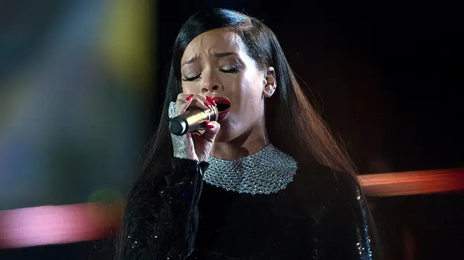 Rihanna performing on stage in a black sparkly dress