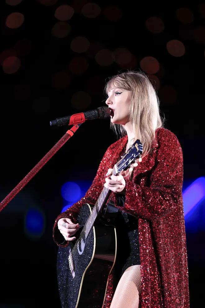 Taylor Swift playing guitar on stage at the Eras tour