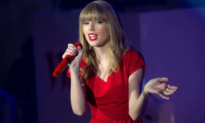 Taylor Swift wearing red dress with a red microphone
