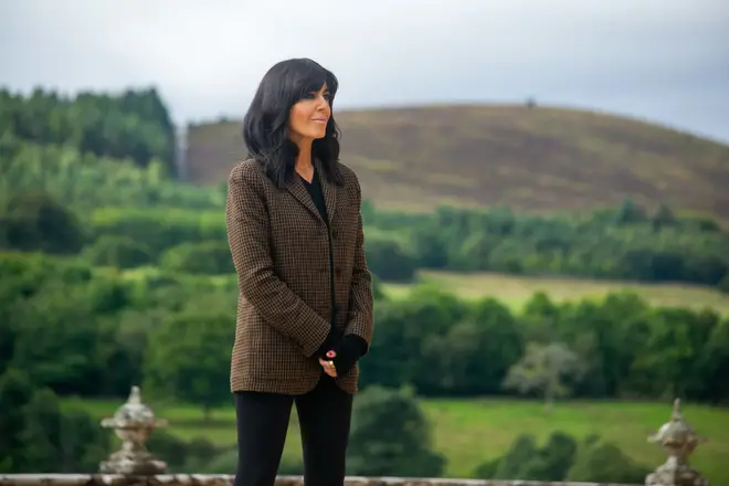 Claudia Winkleman wearing a khaki blazer with a backdrop of hills