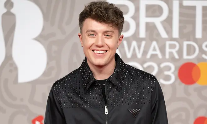 Roman Kemp smiling on the red carpet at the BRITs 2023 wearing a black jacket