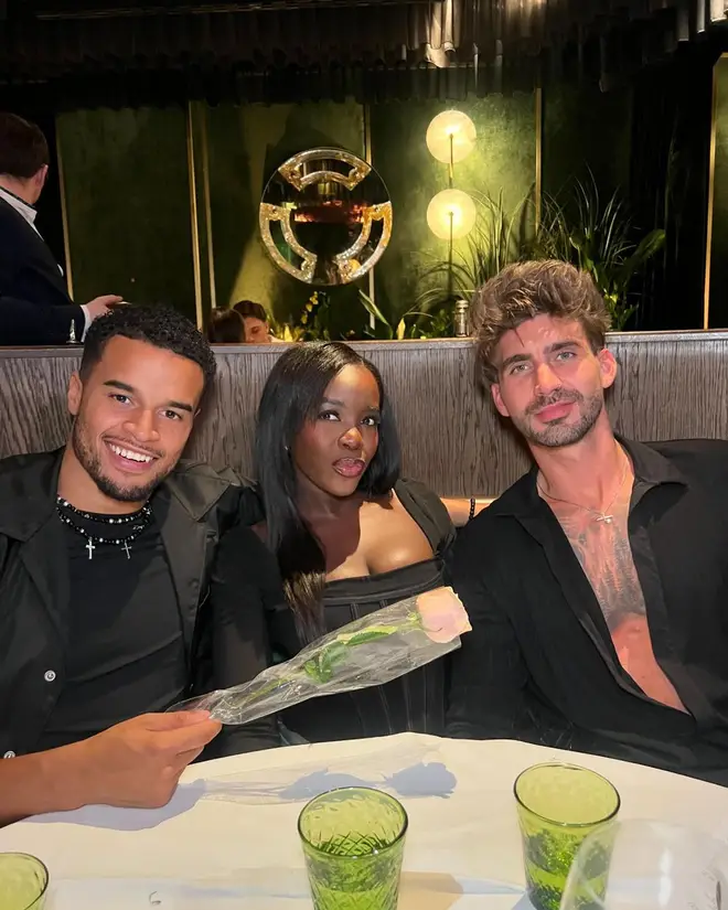 Toby, Kaz and Chris pose together at a dinner table. Toby has a rose in his hand.