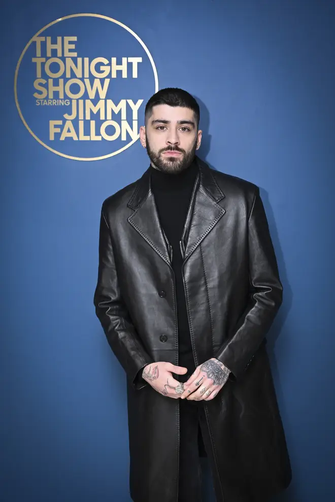 Zayn stands in front of The Tonight Show with Jimmy Fallon sign
